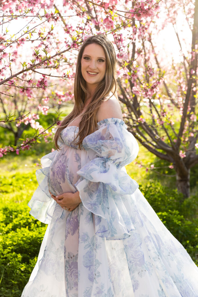 Women standing in front of fruit trees that are in bloom.